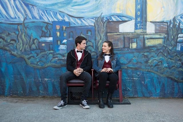 boy and girl talk in front of the bluest wall ever