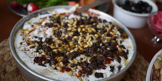 Chicken Fatteh in a serving dish Garnished with sauteed pine nuts