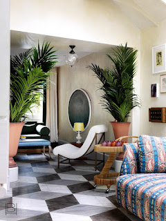 Beata Heuman living room with eighties inspired patterned sofa, black and white geometric tiled floors, and oversized tropical plants