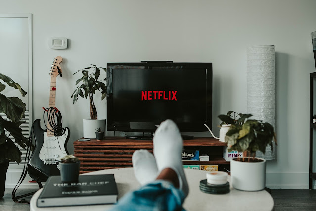 a person watching Netflix and his feet with shoes are visible