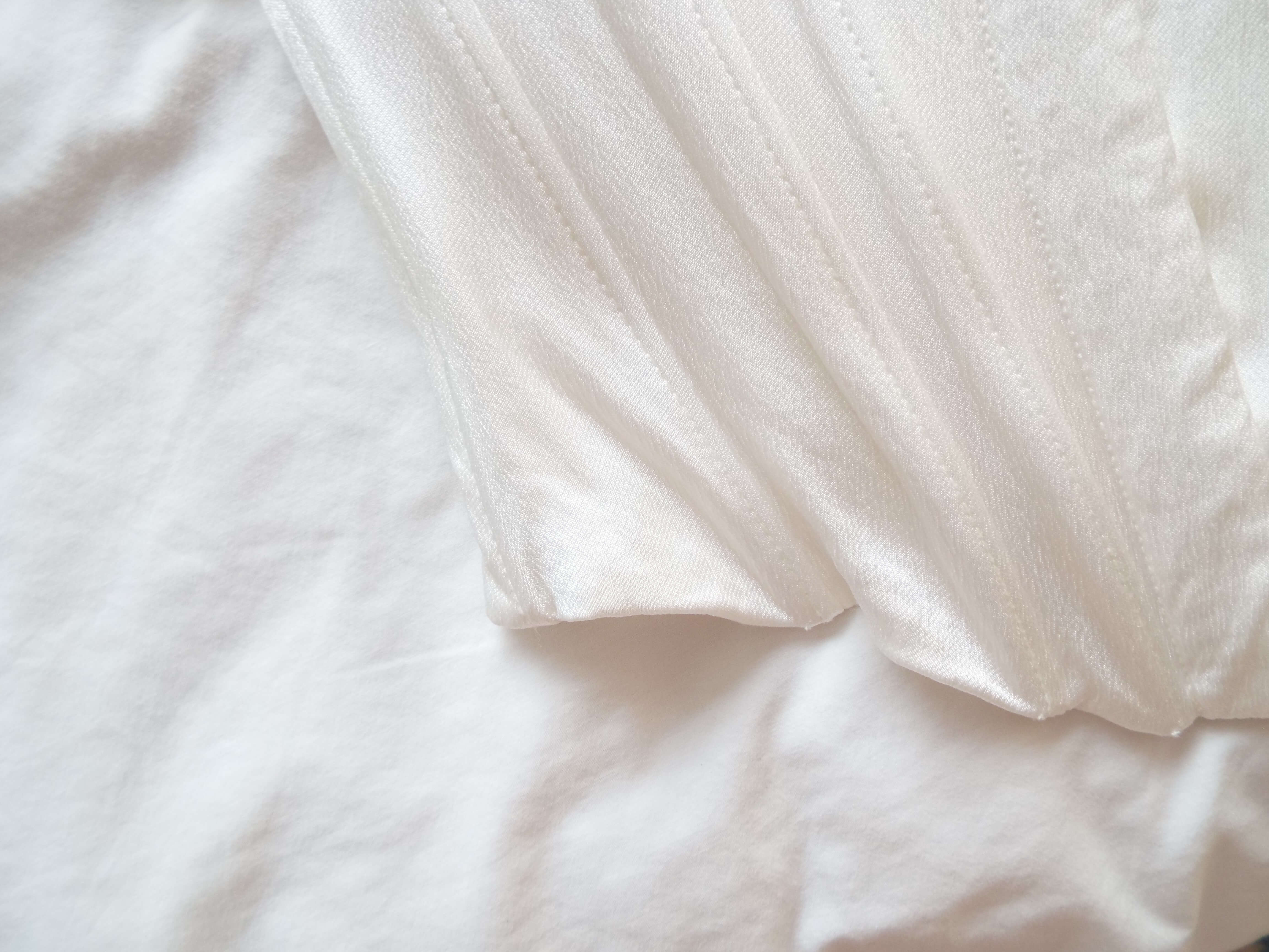 Satin white corset lay on white bedding.