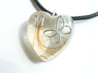 Heart shaped resin pendant containing a lock of hair, silver butterfly and silver initial