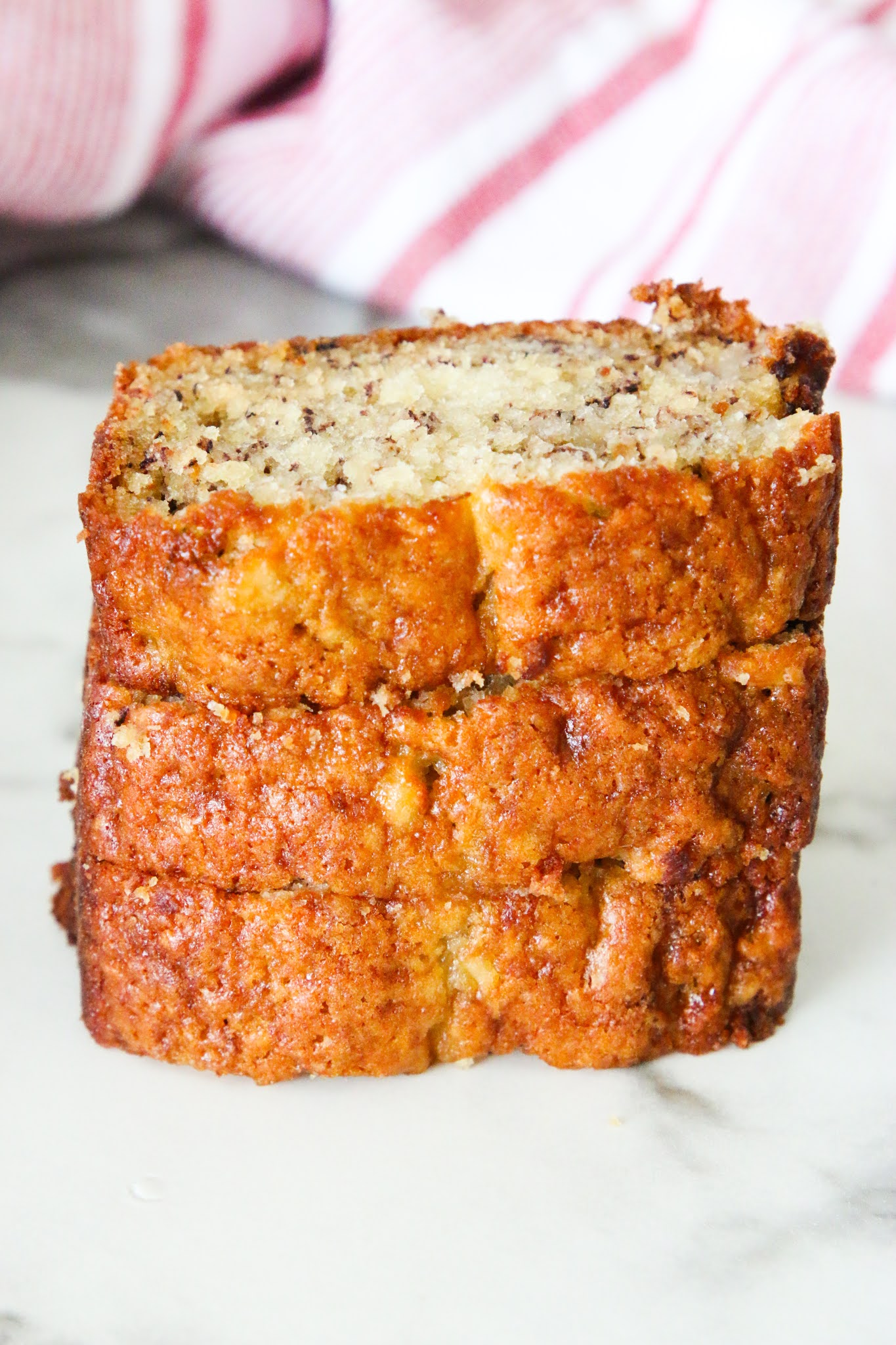 Mini loaf banana bread sliced on a wood platter with a red towel in the background