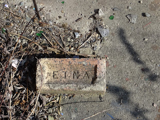 A photo of a brick lying on the ground.  The word ETNA is stamped into it.  Photo by Kevin Nosferatu for the Skulferatu Project.