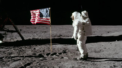 Buzz Aldrin on the Lunar surface looking at the US flag.