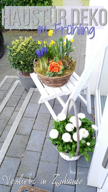 Haustür Deko im Fruehling: Blumen im Pflanzkorb stehen im Eingangsbereich 