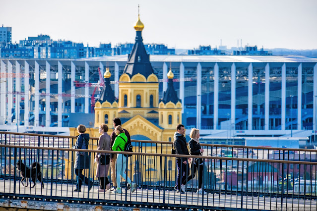 Люди прогуливаются по мостику на фоне Собора Александра Невского