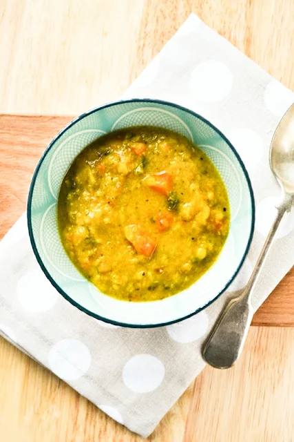 Spiced Carrot, Lentil & Kale Soup in a blue bowl on a spotty linen napkin