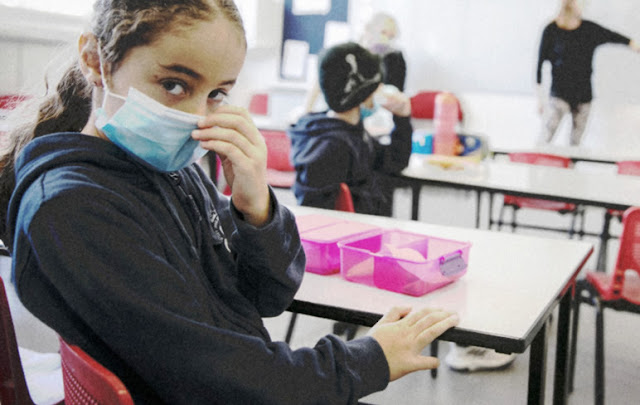 Menina com mascara em sala de aula