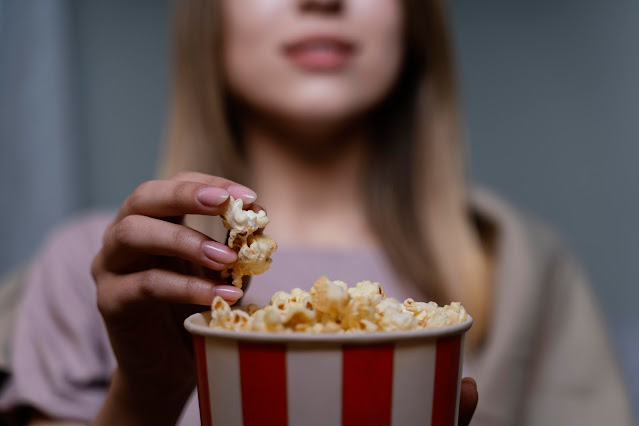 close up of woman eating popcorn and watching tv