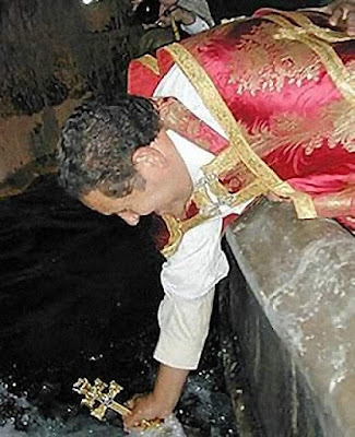 O sacerdote imerge a Cruz na fonte e abençoa as águas