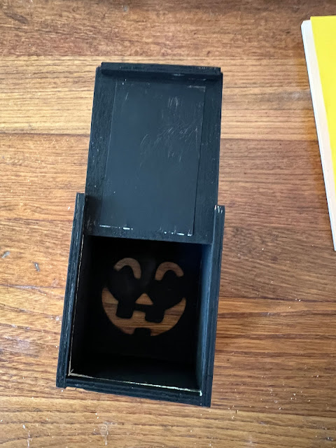Photo of a Dollar Tree Jack O' Lantern box being painted black and orange.