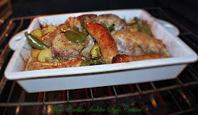 this is a white casserole dish with pork chops and sausage and potatoes baking in the oven