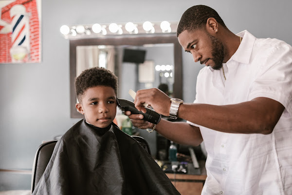 son getting haircut with electric clippers from dad