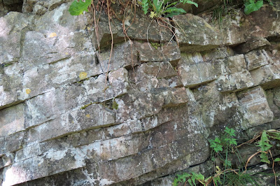 Layers of cracked strata in a rockface, looking almost like man-made bricks.