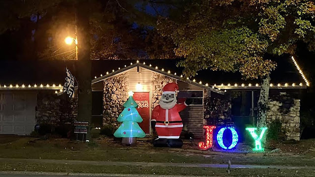 Chris Kennedy’s yard sports a string of white lights, a large, multicolored sign that proclaims “JOY,” a Christmas tree, and an inflatable Black Santa Claus in the middle.