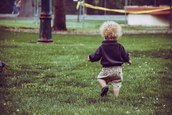 blonde toddler boy running through grass