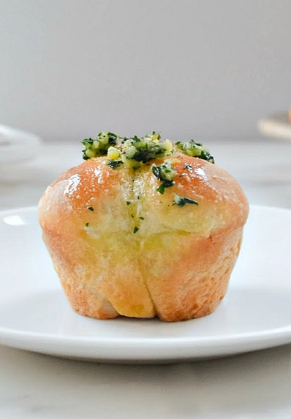 A front shot of a Garlic French Bread Dinner Roll on a white plate.