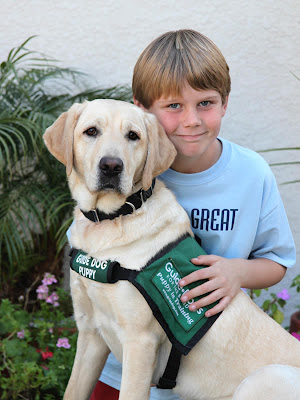 Jimmy Garrison sits with Guide Dog puppy in training Khaki at Jimmy's birthday party. Photo by Pat Whitehead.