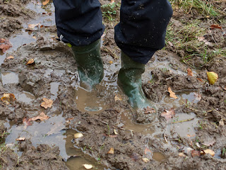 Image of a person's legs with boots stuck in mud