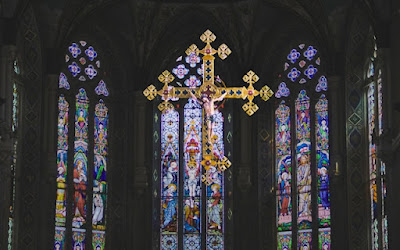 Foto din cadrul unei biserici cu geamuri mari colorate și un crucifix - foto de K. Mitch Hodge - unsplash.com