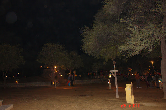 Dark open ground (with a few trees) inside the village of Chokhi Dhani