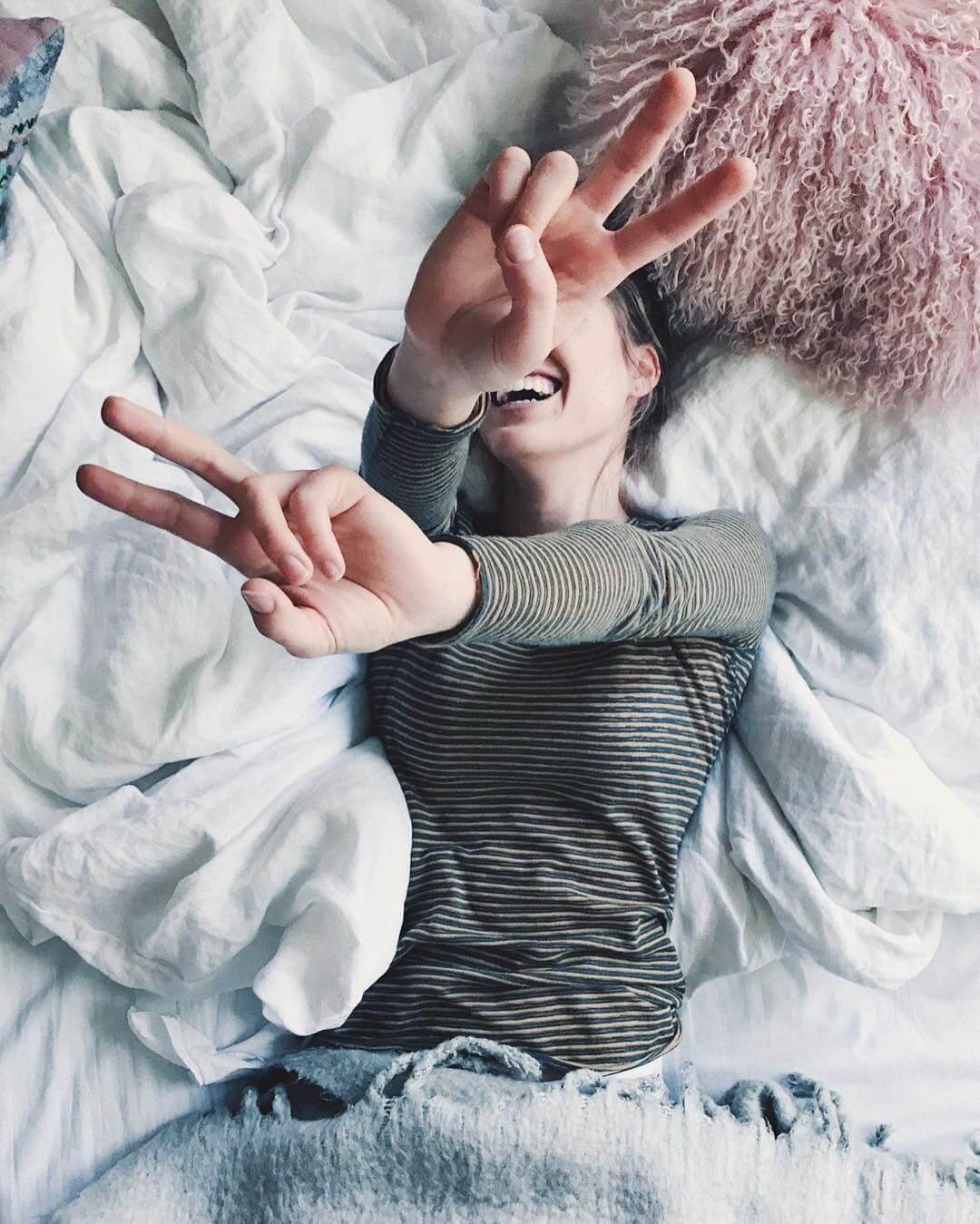 Foto tumblr chica acostada sonriendo en su cama tapandose el rostro