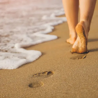 Pies descalzos caminando sobre la arena del mar