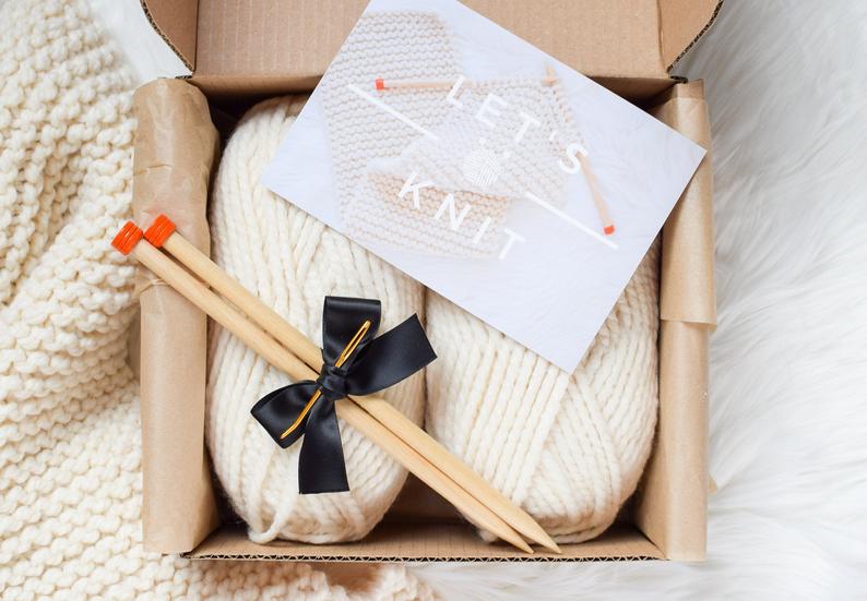 two knitting yarns in a cardboard box with wooden knitting needles