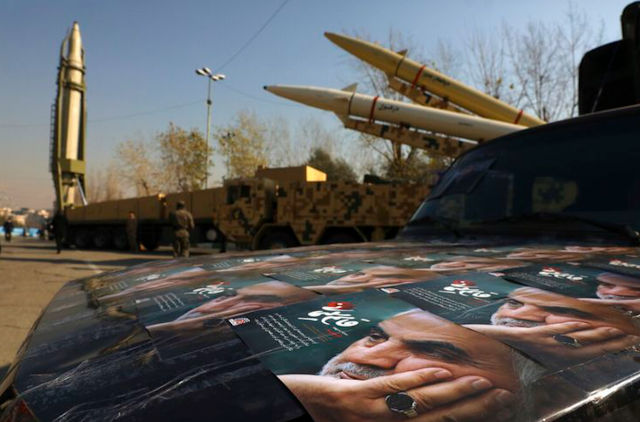 "General Iran Qassem Soleimani, who was killed in Iraq in a US drone strike on January 3, 2020, is seen in front of the Qiam missile (background left), Zolfaghar (top right), and Dezful missiles during an exhibition showcasing missile capabilities by the paramilitary Revolutionary Guard, one day before the second anniversary of Iran's missile attacks on US bases in Iraq in retaliation for the assassination of General Soleimani. (AP PHOTO/VAHID SALEMI)"