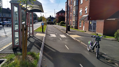 A floating bus stop with a shelter. The road is left and the pavement right with the cycle track between.