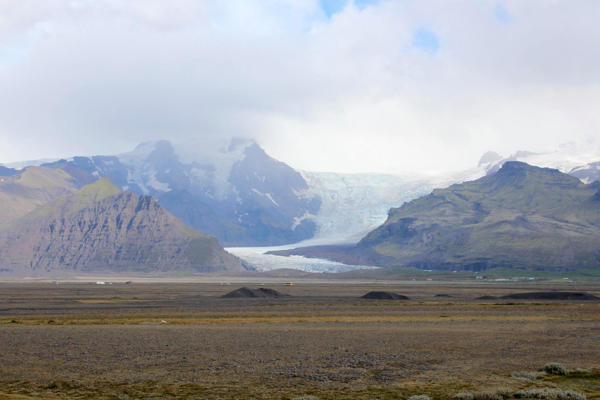 Hvannadalshnúkur peak and glacier rising high next to tiny cars and vans passing by