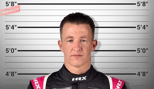 A. J. Allmendinger posing in front of a height chart background
