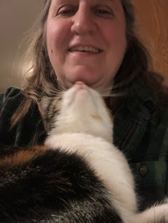 Gift, the cat, cuddles under author G. S. Norwood’s chin.