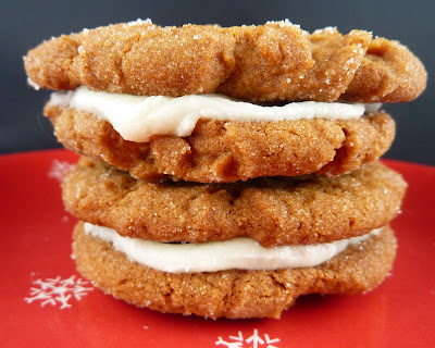 Two ginger sandwich cookies, filled with lemon cream cheese filling, photographed on a red snowflake plate