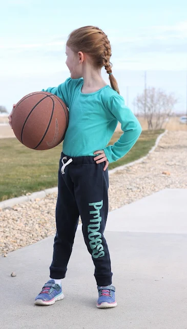 Little girl in jogger pants with basketball