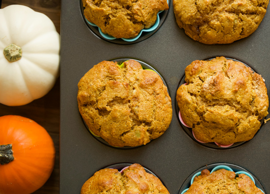 Pumpkin ginger muffins in a muffin pan with a white and orange pumpkin