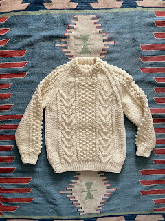 Flat lay image of an aran sweater on a rug
