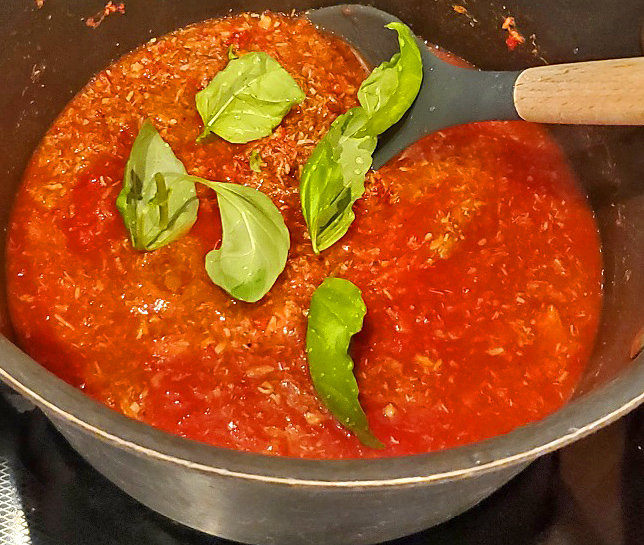 this is a pot of tomato sauce with fresh basil