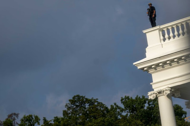 A US Secret Service police officer stands on the roof of the the White House