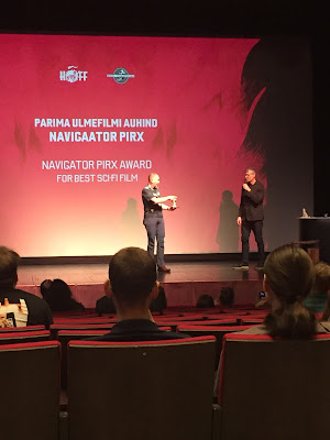 Haapsalu õudukafilmide festival, hetk suurest saalist, festivali lõpetamiselt. Laval on peakorraldaja Helmut ja ulmeühingu president Veiko. Ekraanil kiri Parima ulmefilmi auhind Navigaator Pirx.