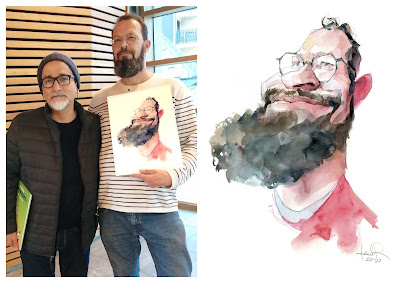 Foto de dos señores barbudos posando con una caricatura de uno de ellos.  A la derecha está la caricatura en acuarela de uno de los dos, larga barba negra, poco pelo y gafas ( es el dibujante belga Jacques Sondron )