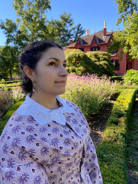 the author from the shoulder up standing in a garden wearing a printed bodice and white embroidered collar