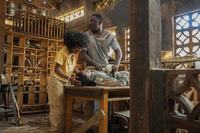 A Black man tries to help his hurt daughter while other daughter looks on