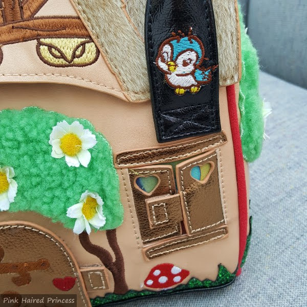 close up of Velcro window on front of bag and bird embroidered handle of handbag