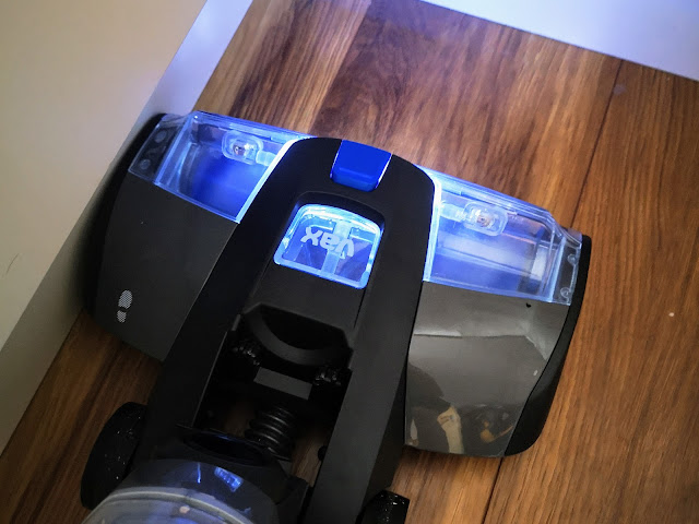 Image of the VAX ONEPWR Hard Floor Cleaner vacuuming close to kitchen cupboards and demonstrating how the LED light helps to identify dirt.