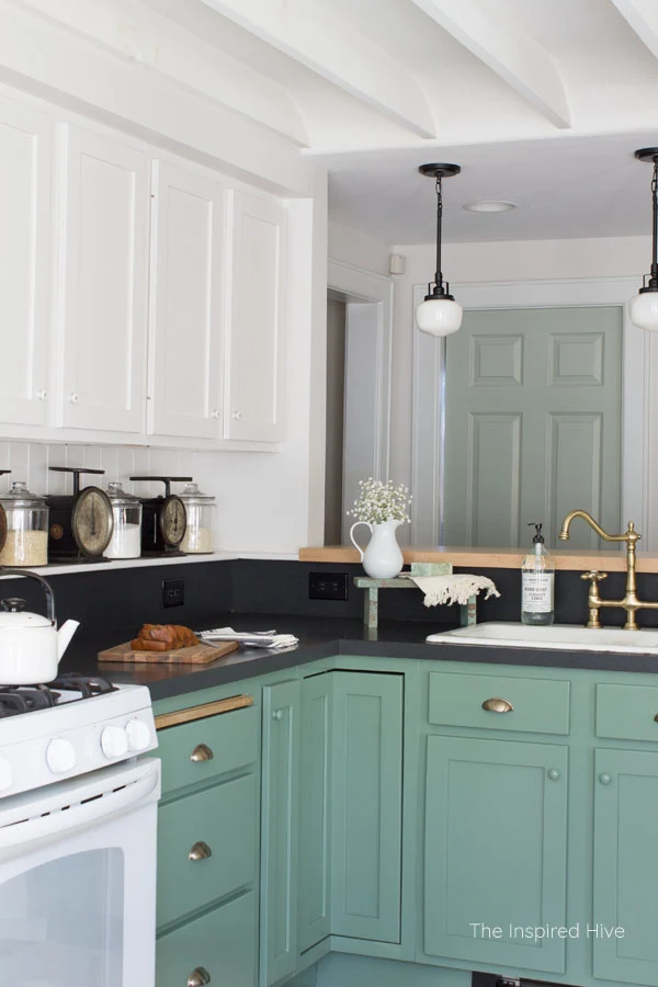 A cozy modern farmhouse kitchen with 1920s vintage charm. Exposed ceiling, schoolhouse lights, brass hardware, and porcelain knobs give this kitchen antique style.