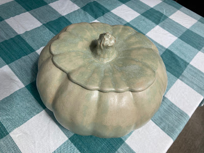 A ceramic pumpkin sitting on a dining room table.