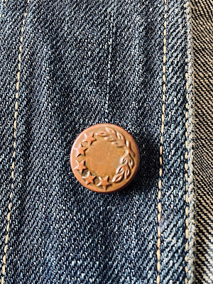 A close up of a vintage button with laurel wreath and stars