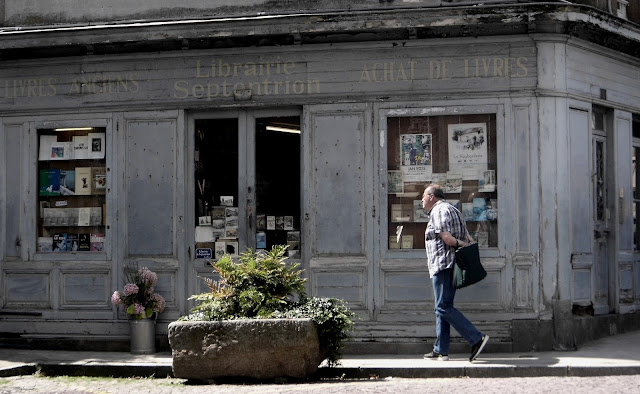 photographie de type ancienne, d'une librairie, avec un passant 